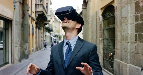 young handsome well dressed businessman with 3d virtual reality glasses enjoys his trip in an adventurous world in a city center. concept of connection technology with nature,science, augmented future
