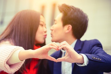 young couple making heart shape with hands.
