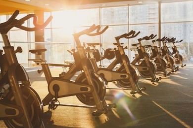 modern gym interior with equipment. fitness club with training exercise bikes in evening backlight.
