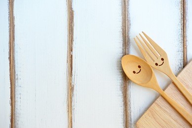 happy wooden fork and spoon with cutting board on wooden texture of dining table. concept about love and relationship with copy space.