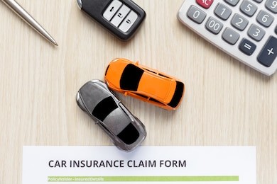 top view of approved car insurance with car key, car toy and calculator on wooden desk - accident concept