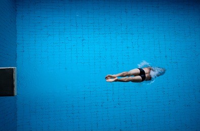 man diving into blue pool water