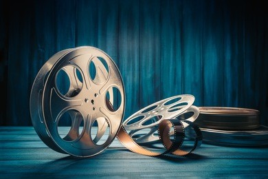 35 mm film reels and cans with dramatic lighting on a wooden background