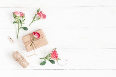 flowers composition. gift and rose flowers on wooden white background. flat lay, top view.
