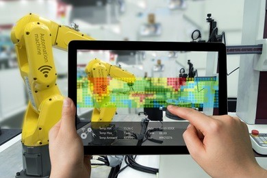 industry 4.0 concept .man hand holding tablet with augmented reality screen software and blue tone of automate wireless robot arm in smart factory background