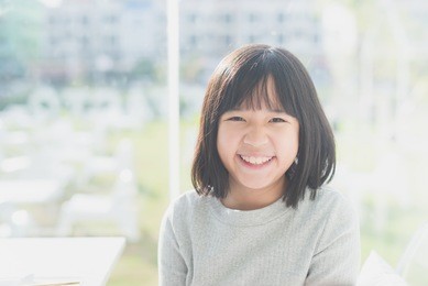 portrait of cute asian girl sitting in a restaurant under sunlight