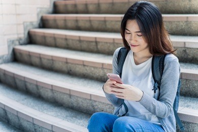 woman students sitting on stairs with their smartphones