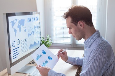 investor analyzing financial reports and key performance indicators (kpi) of stock market on the computer screen with business intelligence (bi) analytics and graphs at the office