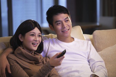 young couple sitting on sofa watching tv together