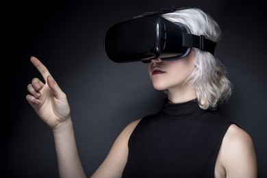 woman wearing a virtual reality headset touching or holding something.  she is interacting with something she is watching or playing a video game.  the image depicts vr and ar technology.