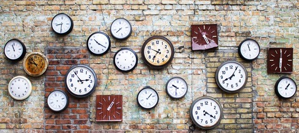 collection of vintage clock hanging on an old brick wall