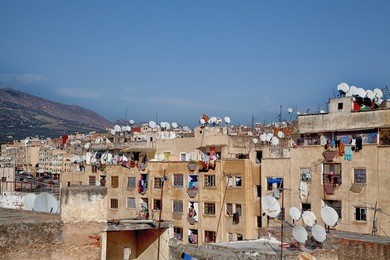 backstreet atmosphere in the old kingdom city fes in morocco, africa, with a lot of satellite dishes and a luminous shining blue sky