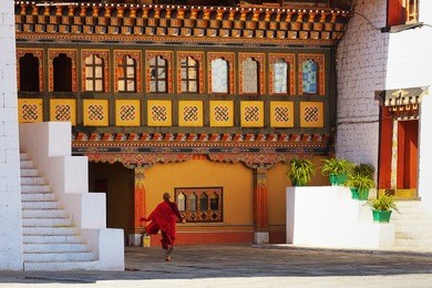 architecture of bhutan. young monk runs in paro dzong, xvii century, buddhist monastery and a fortress, bhutan, asia.