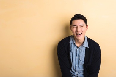 asian young man laughing in the studio yellow background