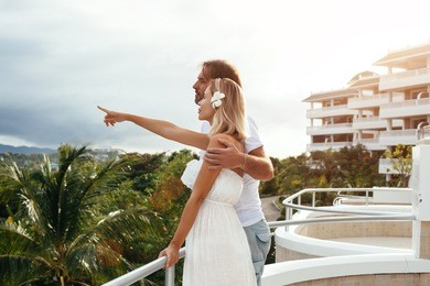 couple celebrating honeymoon on a hotel balcony with a beautiful view.