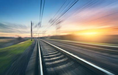 railroad in motion at sunset. railway station with motion blur effect against colorful sky, industrial concept background. railroad travel, railway tourism. blurred railway. transportation. vintage