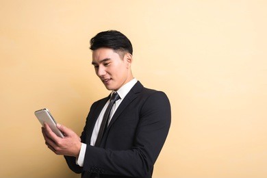 asian business man use smart phone, closeup portrait on studio yellow background