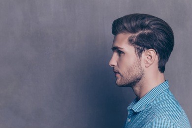 profile of handsome smiling young man on gray background
