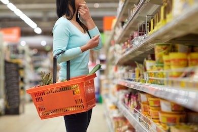 sale, shopping, consumerism and people concept - woman with food basket at grocery store or supermarket