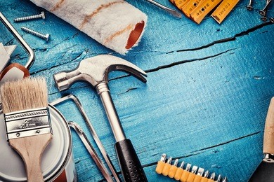 set of various tools on blue wooden background. construction and renovation concept with copy space
