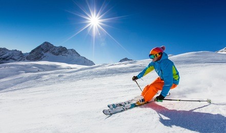 skier skiing downhill during sunny day in high mountains