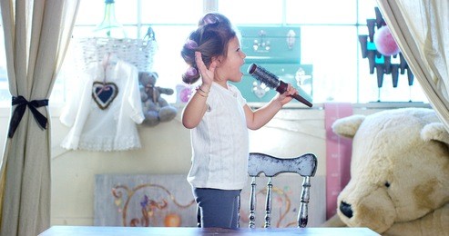 at home, in the bedroom, the girl singing and fun using the brush as a microphone. concept: beauty, family, fun, music.