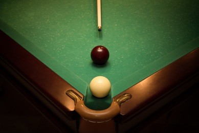 balls and cue for russian billiards on green table near with hole, vignette