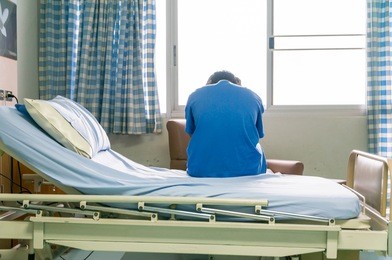 male patient sitting on hospital bed.