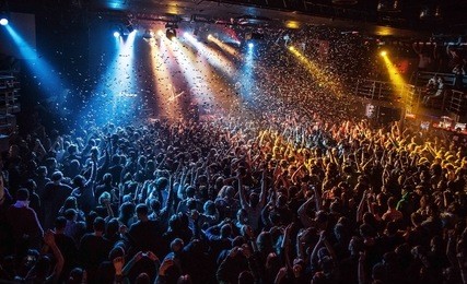 shiny rainbow confetti during the concert and the crowd of people silhouettes with their hands up. dark background, smoke, concert  spotlights. bright lights