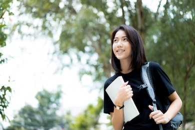 a female college student reading a book while lying on the park