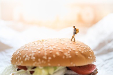 travel and food concept. traveler miniature figure toy walking on top of beef burger.