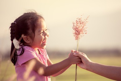 happy asian little girl giving grass flower to her mother with love in vintage color tone