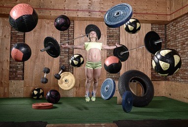 sporty girl levitates in a gym environment,a rowing machine,balls,dumbbells,stationary bike
