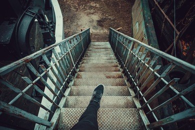 man going down on metal stairs, first person look, dramatic colors