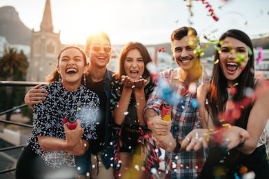 group of friends enjoying party and throwing confetti. friends having fun at rooftop party.