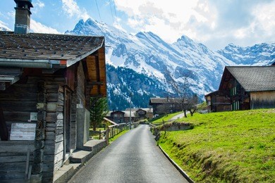 the snow-covered swiss alps in background and green field at murren village, jungfrau region, switzerland - april, 2016