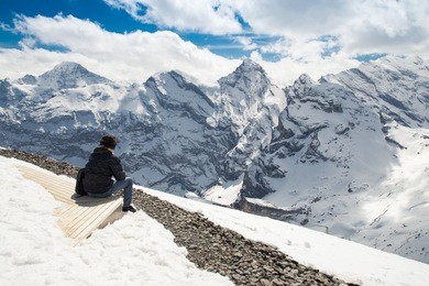 alps scenery with young happy man from the top of schilthorn, switzerland - april, 2016