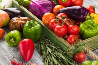 set of different fresh raw colorful vegetables in the wooden tray, light background