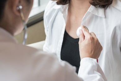 doctor examining woman patient's heart health checkup using stethoscope in medical clinic   