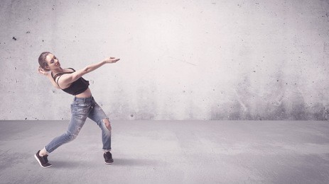 a beautiful young hip hop dancer dancing contemporary urban street dance in empty clear grey wall background concept.