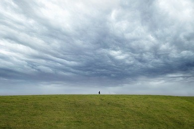 person walking on the horizon with dark dramatic sky behind. 
