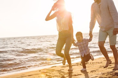happy young family have fun on beach run and jump at sunset
