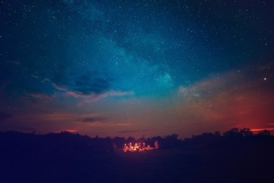 camping fire under the amazing blue starry sky with a lot of shining stars and clouds. travel recreational outdoor activity concept.
