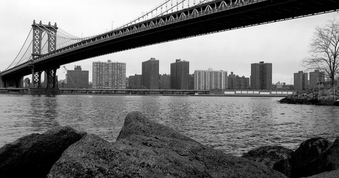 black and white view of the east river under the manhattan bridge from the dumbo beach in brooklyn (new york, usa january, 2017). 