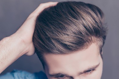 close up photo of man combing his hair with fingers.