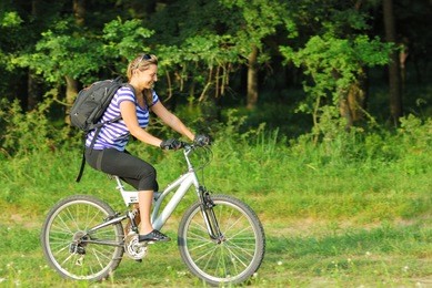 happy blonde young woman traveling on country side with bike