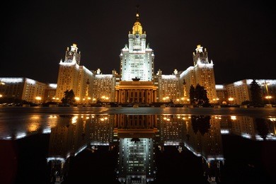 main building of lomonosov moscow state university. fall. evening. cars near building. building is reflecting in puddle.