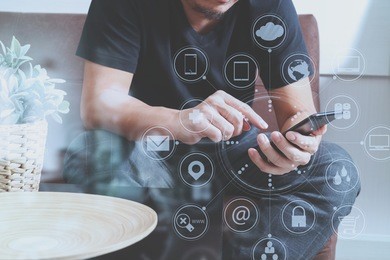 designer man hand using smart phone for mobile payments online shopping,omni channel,sitting on sofa in living room, wooden tray on table,virtual icons graphics interface screen