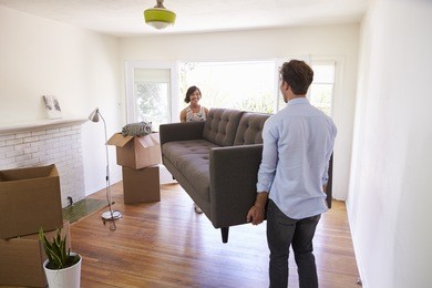 couple carrying sofa into new home on moving day