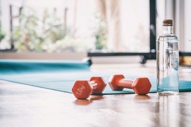 yoga mat and a pair of weights dumbbells on wooden floor